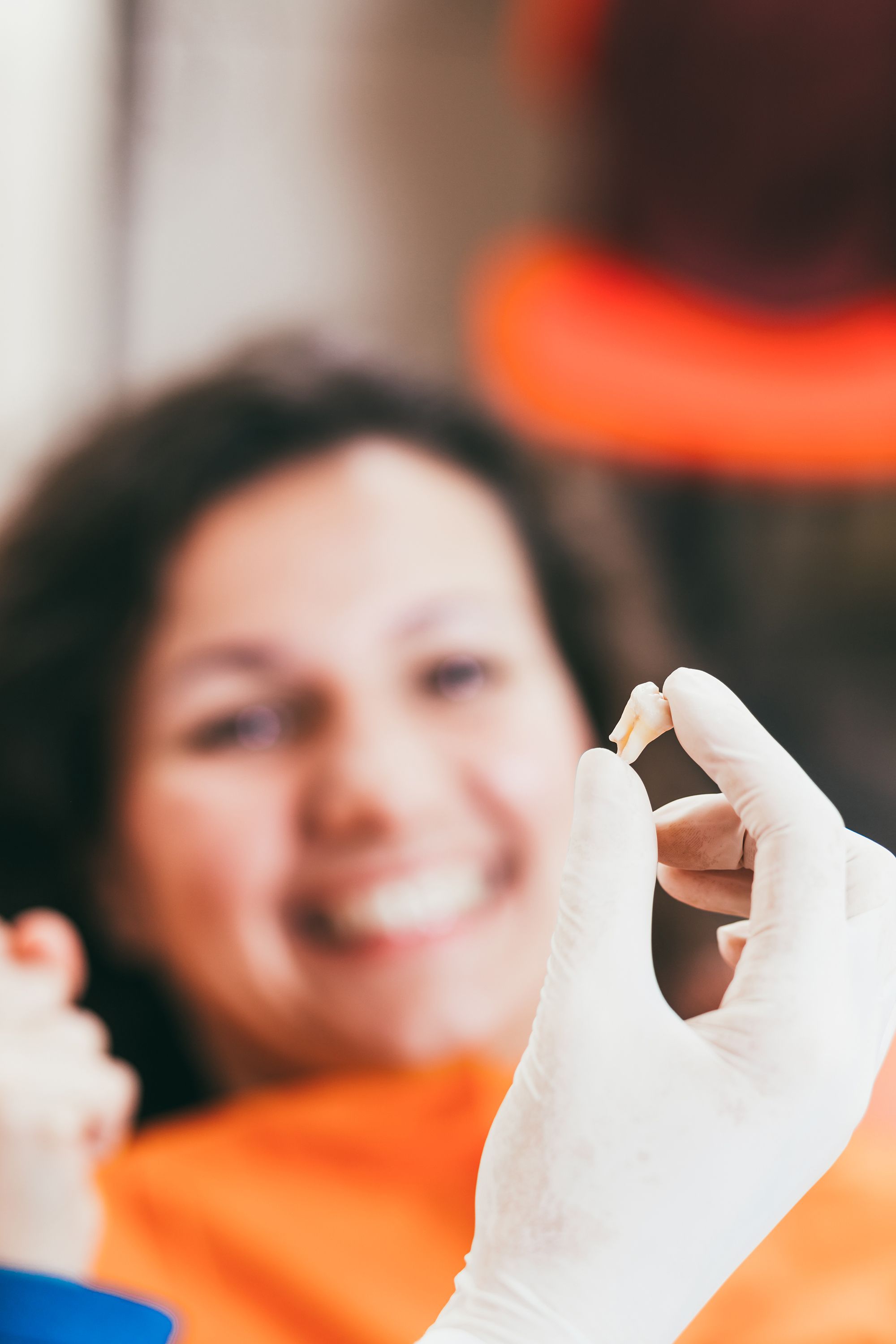 Dentist holding extracted tooth in front of smiling patient